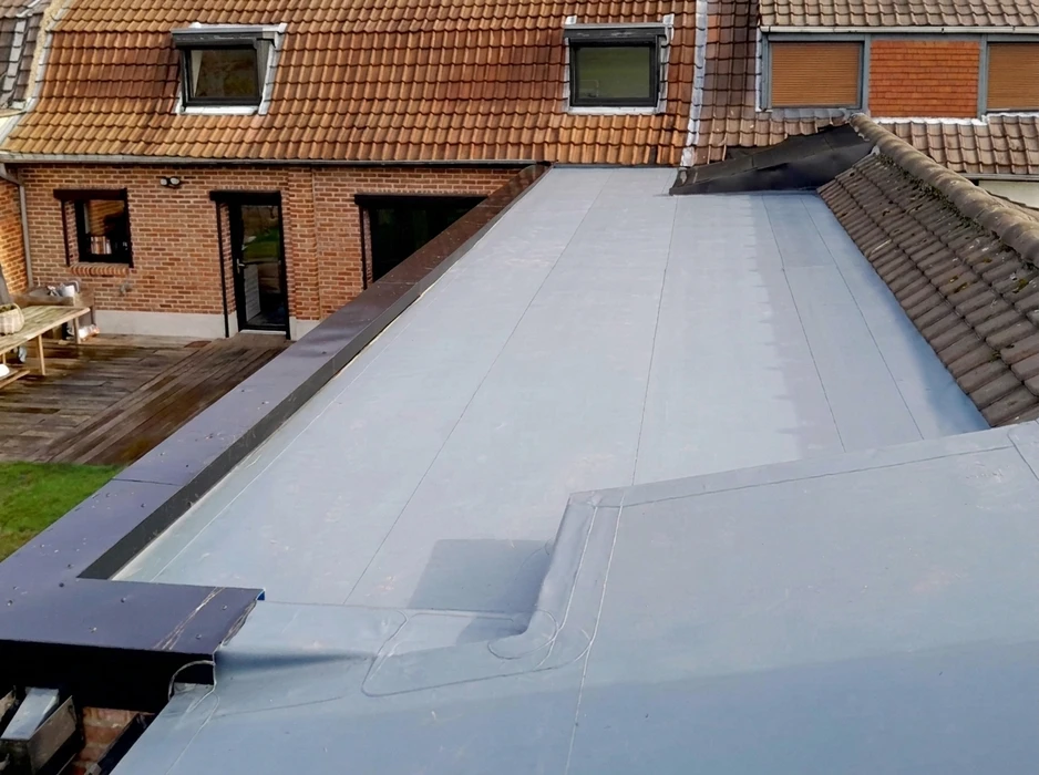 Vue aérienne d'une toiture plate recouverte d'une membrane EPDM grise, récemment posée sur une extension de maison en briques rouges
