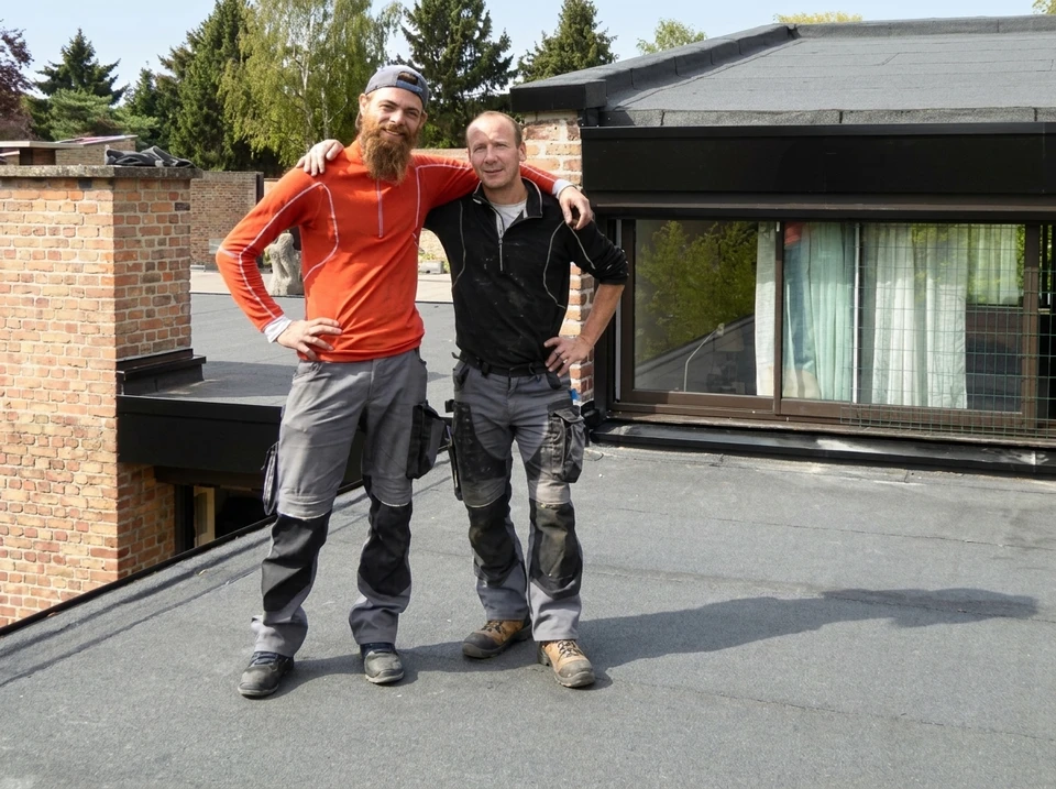 Chantier de construction en extérieur avec ouvriers installant une membrane d'étanchéité sur toiture-terrasse
